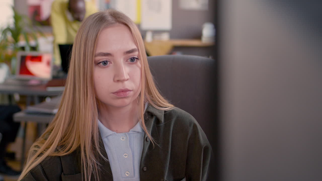 сосредоточенная молодая девушка смотрит на монитор компьютера в анимационной студии