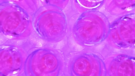 Close-up-of-champagne-glass-in-top-shot,-pink-color-because-it-is-the-lights-of-the-student-gala-evening