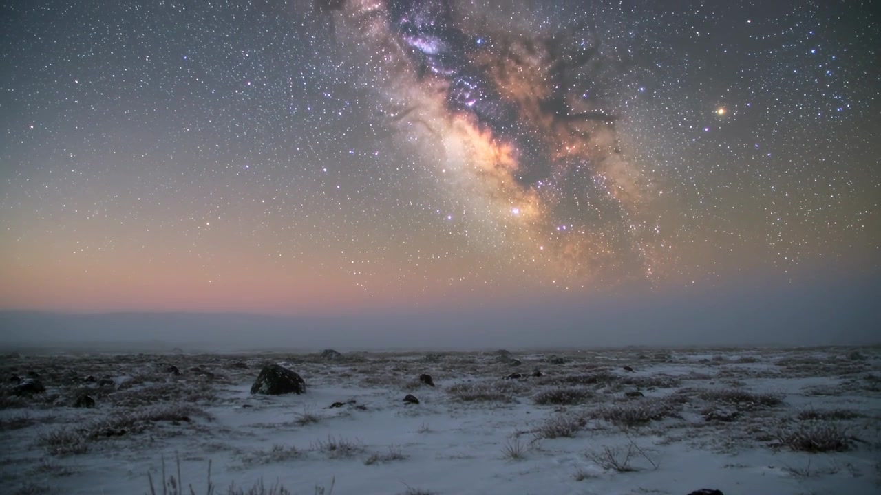 Melkeveiens skiftende kjerne beveger seg over stjernehimmelen under et time-lapse-opptak, med en snødekt slette under.