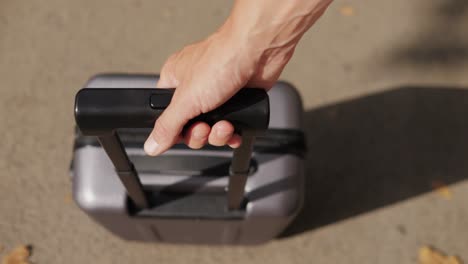 person holding a gray rolling suitcase