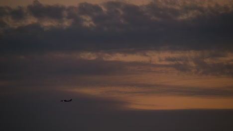 airplane flying above dramatic sunset clouds