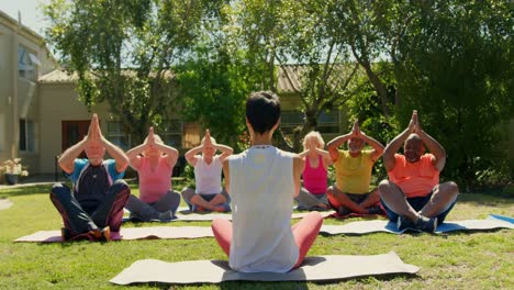 rear view of female trainer training senior people in performing yoga at fitness studio 4k