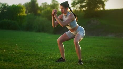 Una-Mujer-Joven-Salta-Un-Ejercicio-De-Burpee-En-Un-Parque-Sobre-El-Césped-Al-Atardecer.-Entrenamiento-Físico-En-Cámara-Lenta-De-Una-Mujer-Joven-En-Un-Prado