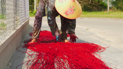 Asian-woman-separating-straws-to-dry-on-the-sun-before-weaving-them-into-rug-or-mattress