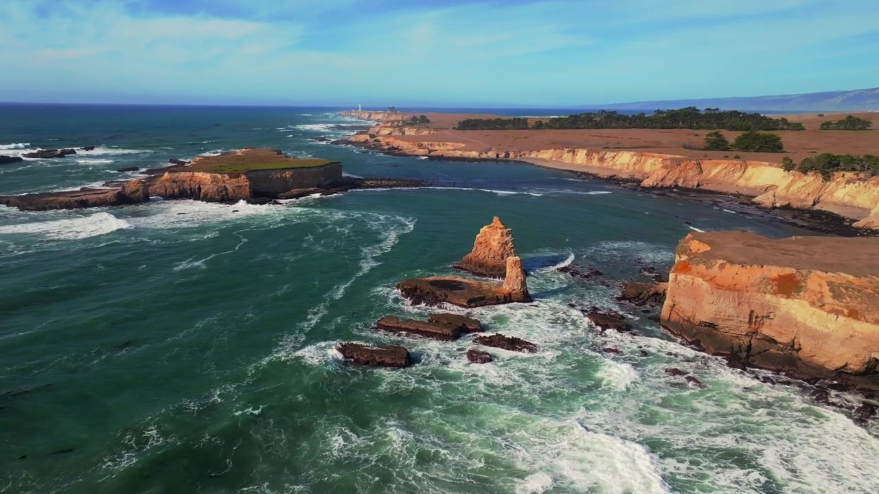 Vista aerea con drone, di giorno e soleggiata, delle isole della costa di Mendocino e del Faro di Point Arena Rock. La frastagliata costa californiana con onde, mareggiate e formazioni rocciose, da Fort Bragg a San Francisco, sull'Oceano Pacifico settentrionale. Ripresa costiera in avanti e verso l'alto.