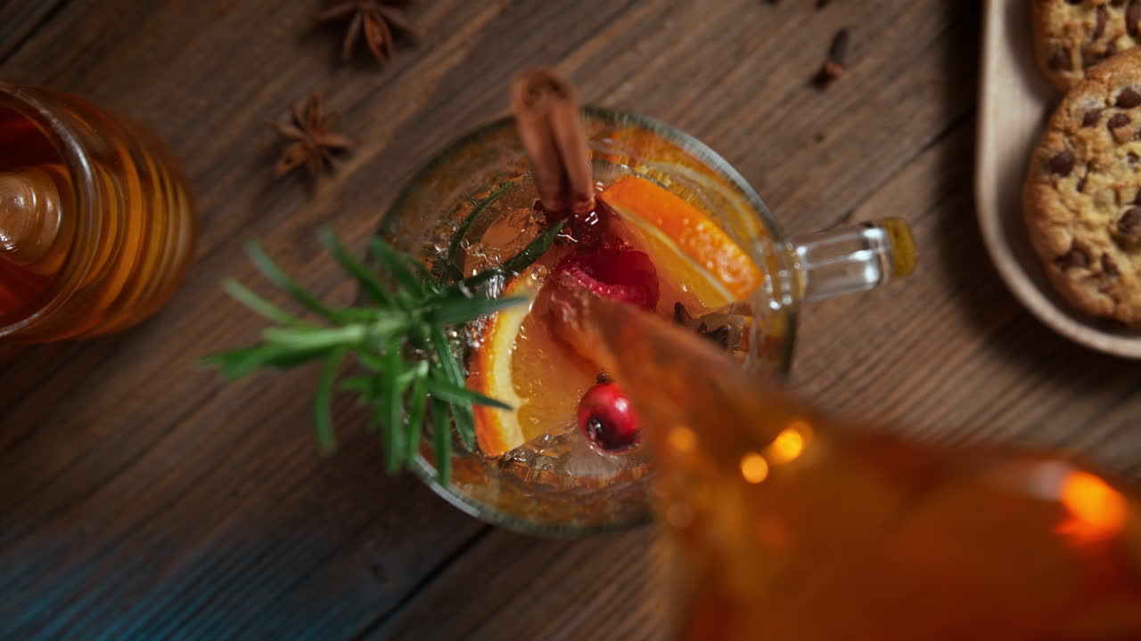 Preparing Warming Winter Tea With Orange, Cinnamon, Rosemary And Anise - Table Top View of the Stream Pouring to the Cup
