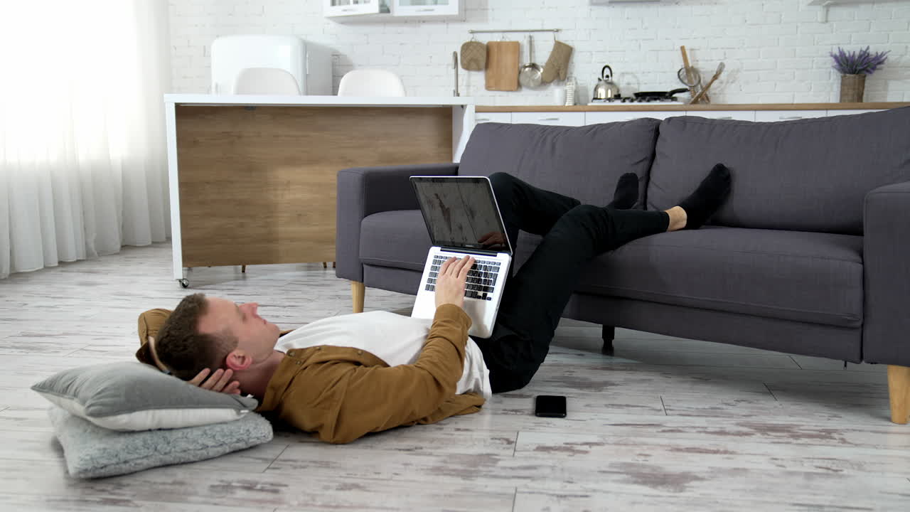 Man with laptop on floor. Young man using laptop at home, lying on the floor