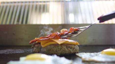 Colocar-Tocino-En-Una-Hamburguesa-Con-Queso-En-Un-Restaurante-De-Comida-Rápida-Cerrar-A-Cámara-Lenta