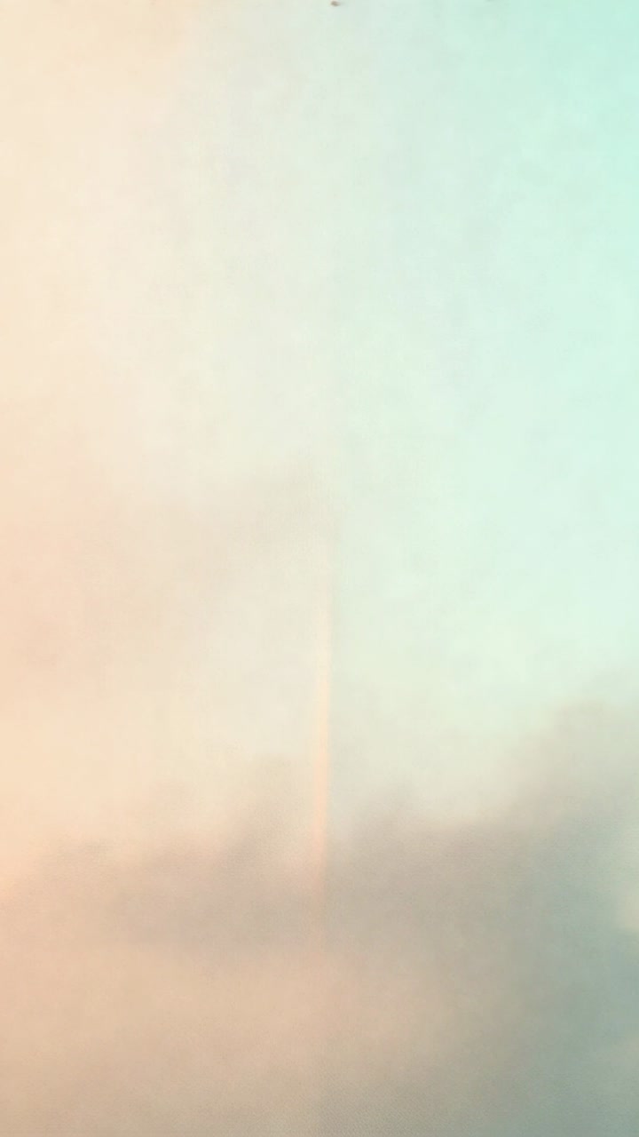 Vertical video: Camera recording centered streak rising above clouds, dark speck appearing at dawn