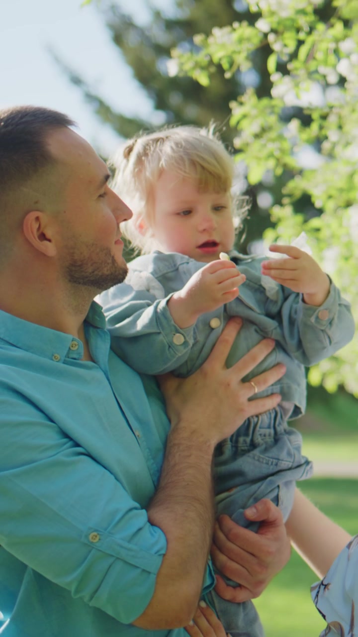 Un padre tiene il suo bambino vicino in un parco illuminato dal sole. Il bambino guarda in alto con meraviglia e gioia. La scena cattura teneri momenti familiari all'aperto. Ideale per contenuti su genitorialità, natura o famiglia emotiva