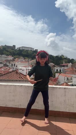young girl dancing on a rooftop with headphones