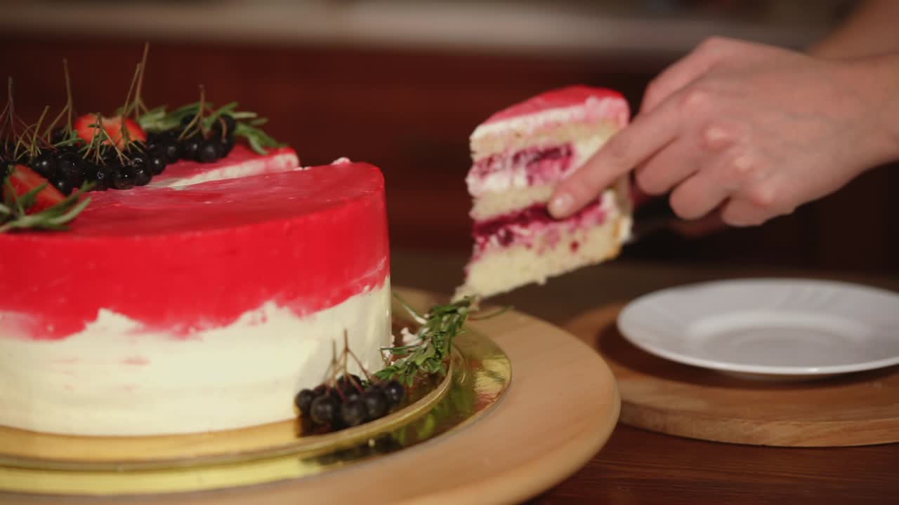 persona cortando un pastel de capa de terciopelo rojo con bayas