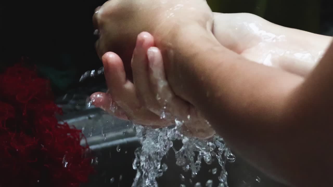Close-up view of hands being washed under running water with soap, focusing on thorough cleaning techniques.