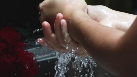 close-up view of hands being washed under running water with soap, focusing on thorough cleaning techniques.