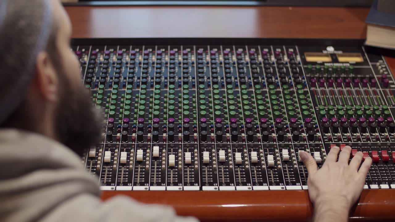 Man in a control room of a recording studio moving a fader with a Toft console - Professional recording studio - 4K at 60fps (slowmotion) - Professional audio vives