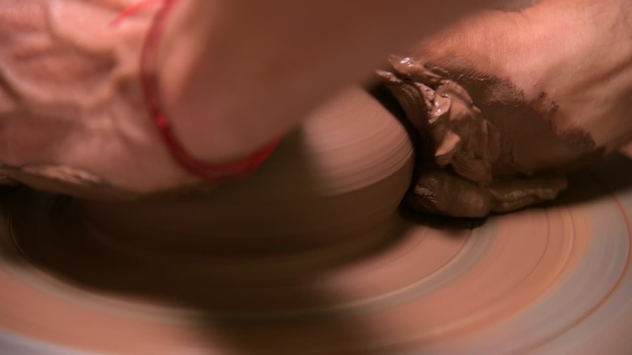 Primo piano di mani maschili che creano una ciotola di argilla su un tornio da vasaio. Artigianato e produzione di esclusive stoviglie da tè in argilla