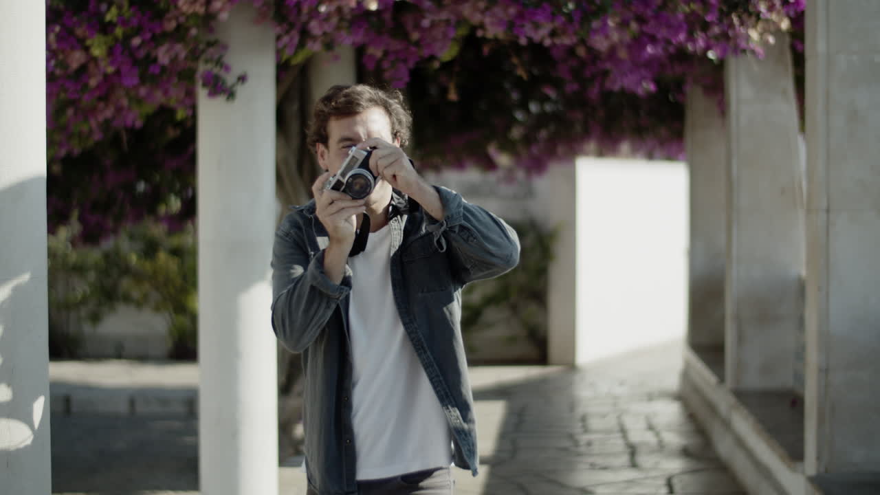 vista frontal de un joven caucásico tomando una foto con la cámara.