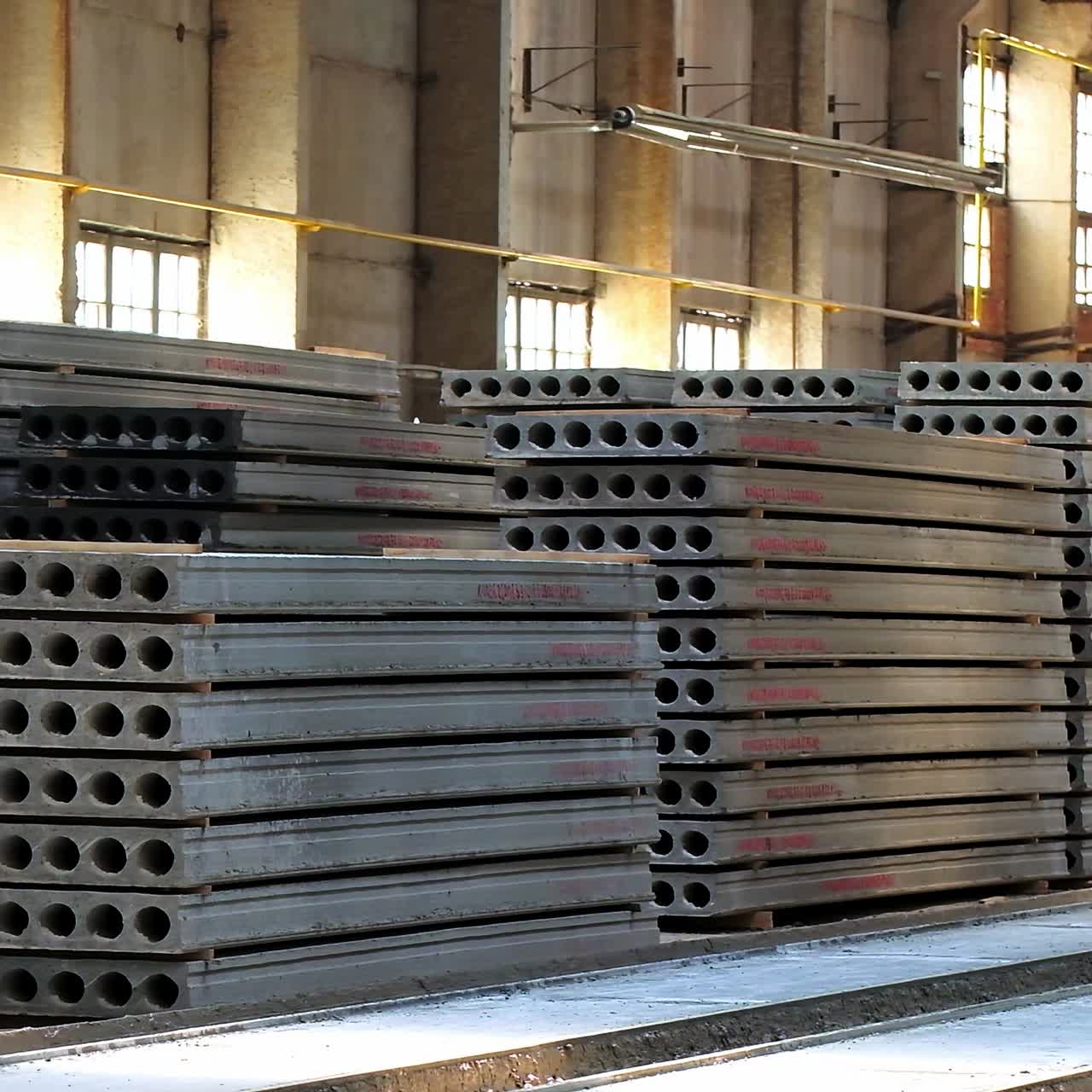 The armored concrete plates with holes inside stacked in piles. Ferroconcrete materials inside the construction industrial plant