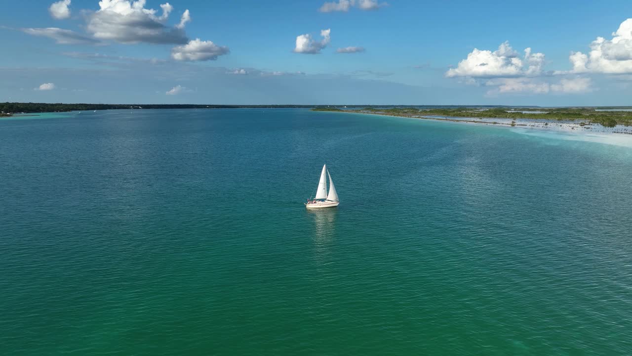 vista aérea acercándose a un velero en aguas turquesas del lago en la laguna bacalar, soleado méxico