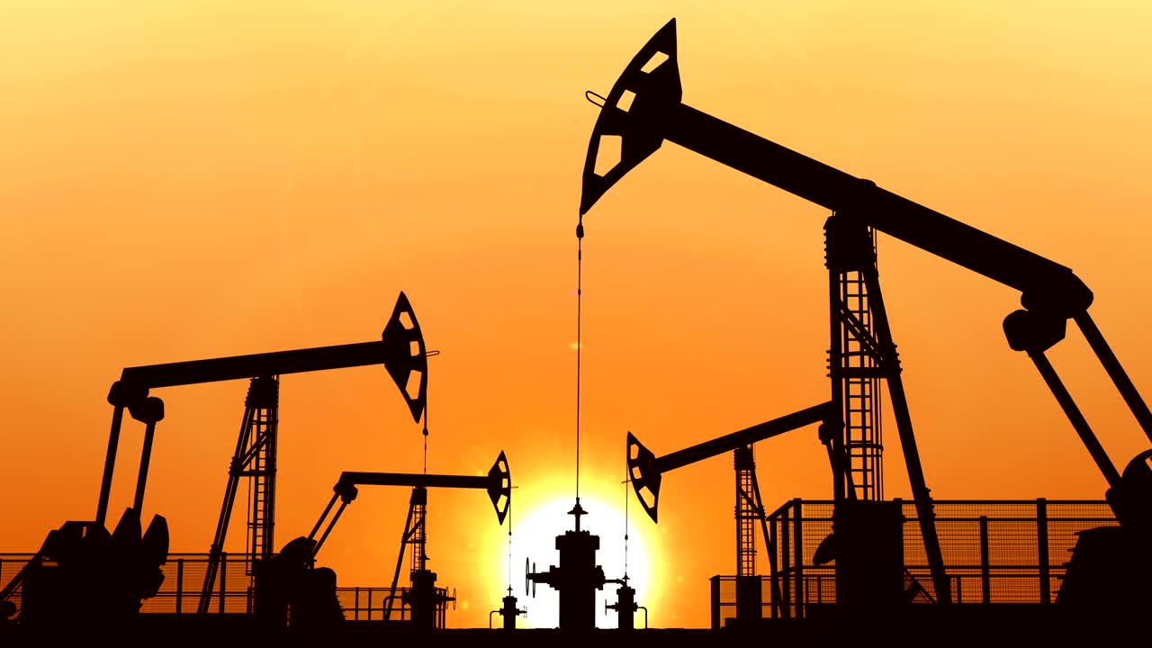 bombas de aceite en bucle contra el cielo naranja al atardecer