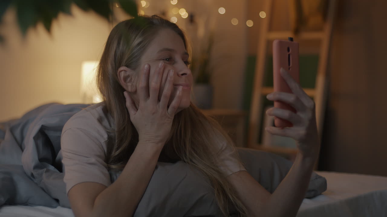 Woman taking a selfie in bed at night
