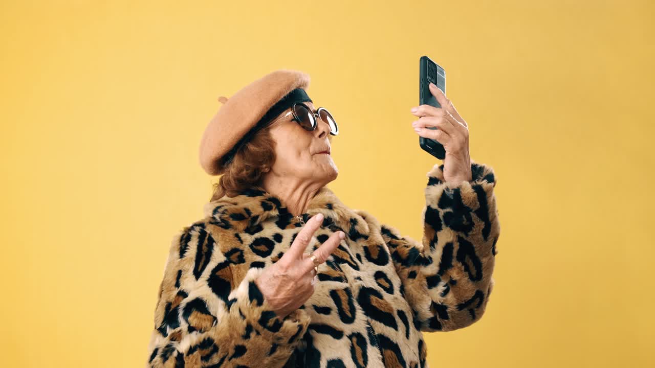 mujer mayor elegante sonriendo mientras tiene una llamada de video o graba un video en su teléfono móvil.