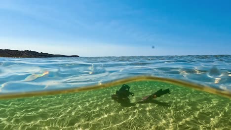 vista submarina dividida en cámara lenta inusual de aletas de buceo aisladas perdidas descansando en el fondo marino