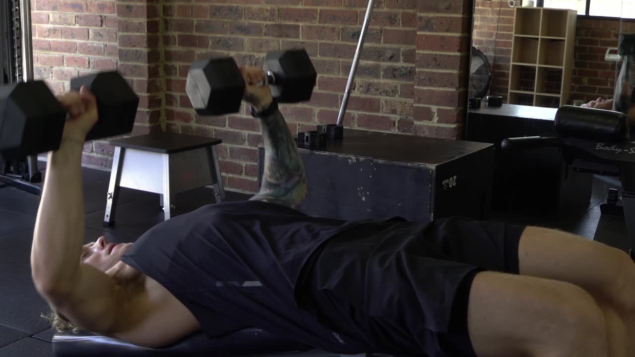 측면 감소 덤벨 가슴 프레스에서 샷을 운동하는 홈 체육관에서 근육질의 남자