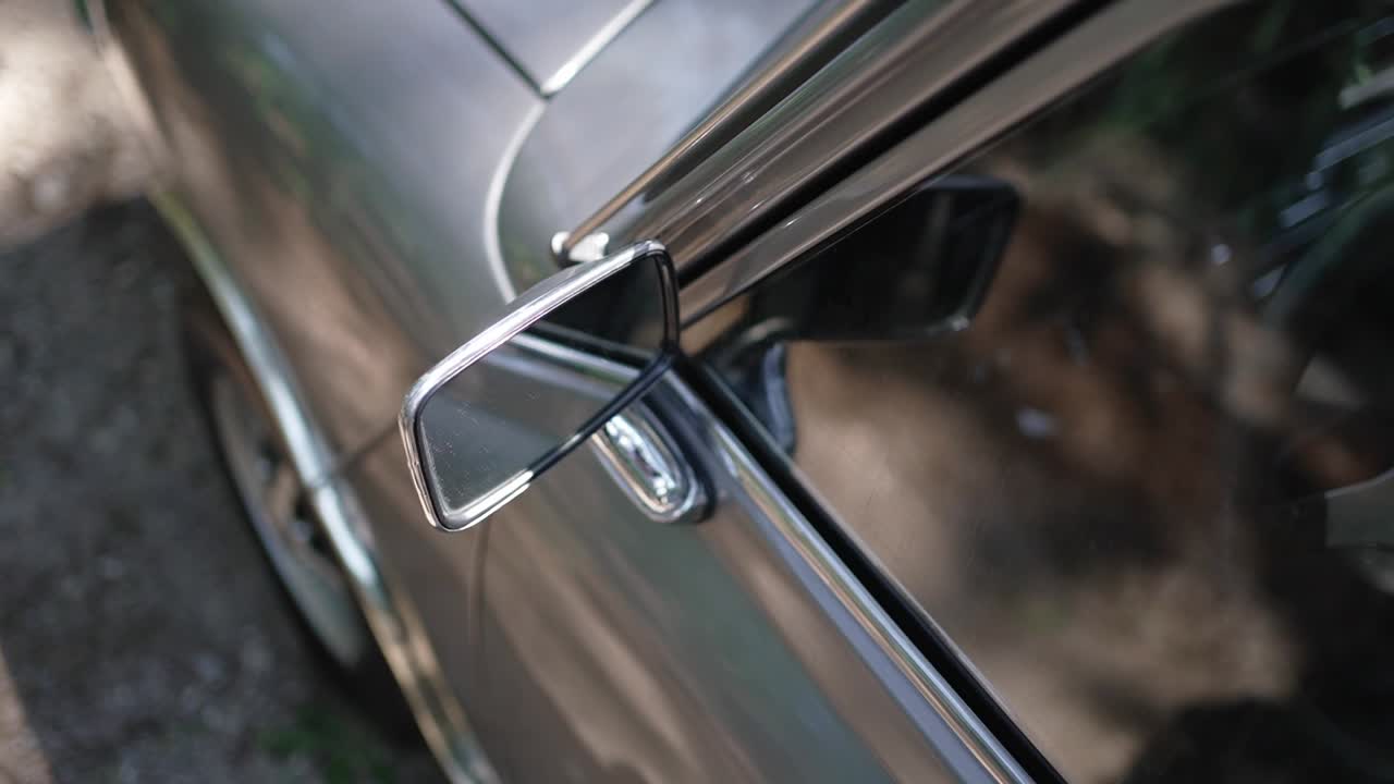 Vintage car side mirror with chrome details reflecting natural outdoor light
