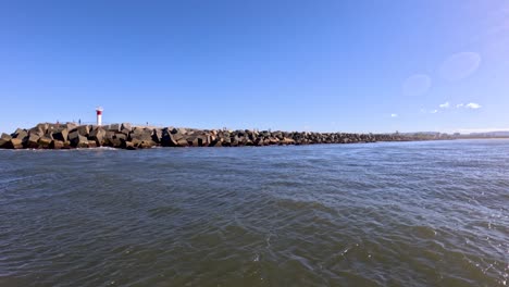 boat moving past rocky breakwater in gold coast