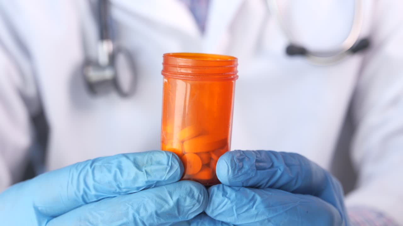 Médico(a) segurando um frasco de comprimidos