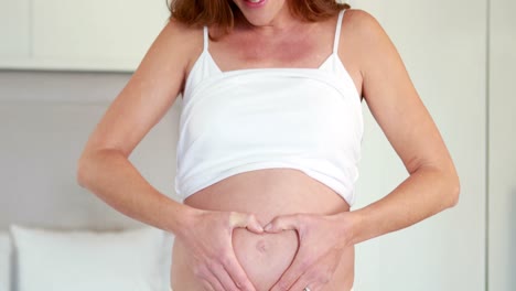 pregnant woman making heart shape on bump