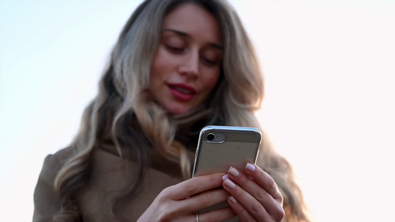 Smiling young woman typing in her phone in park