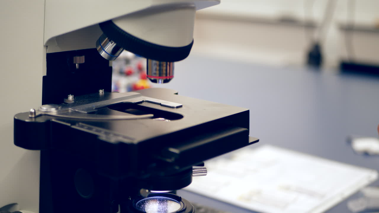 A college professor preparing slides of human cells for a microscope to show students in a biology research lab SLIDE LEFT