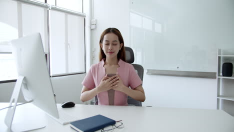 a woman in an office setting engages in mindfulness meditation to promote calmness and focus.