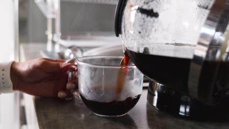 chica que se sirve una taza de café negro por la mañana