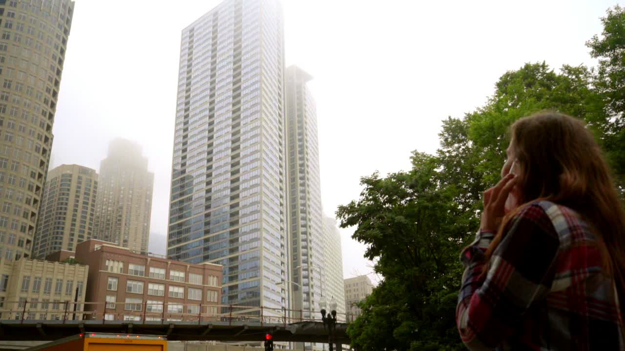 도시 건물을 바라보는 여성. 스마트폰으로 이야기하는 젊은 갈색 여성