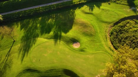 high angle aerial orbit rotation drone shot flying above green golf course during sunny summer day