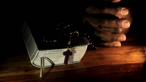 rezando a dios con las manos junto con la biblia y el hombre cruzado del caribe rezando con fondo negro almacen de video