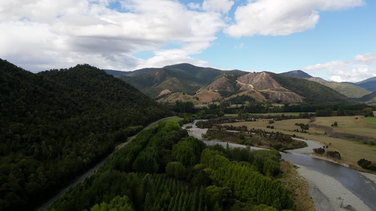 Scenic road leading through panoramic New Zealand woods and hills with river