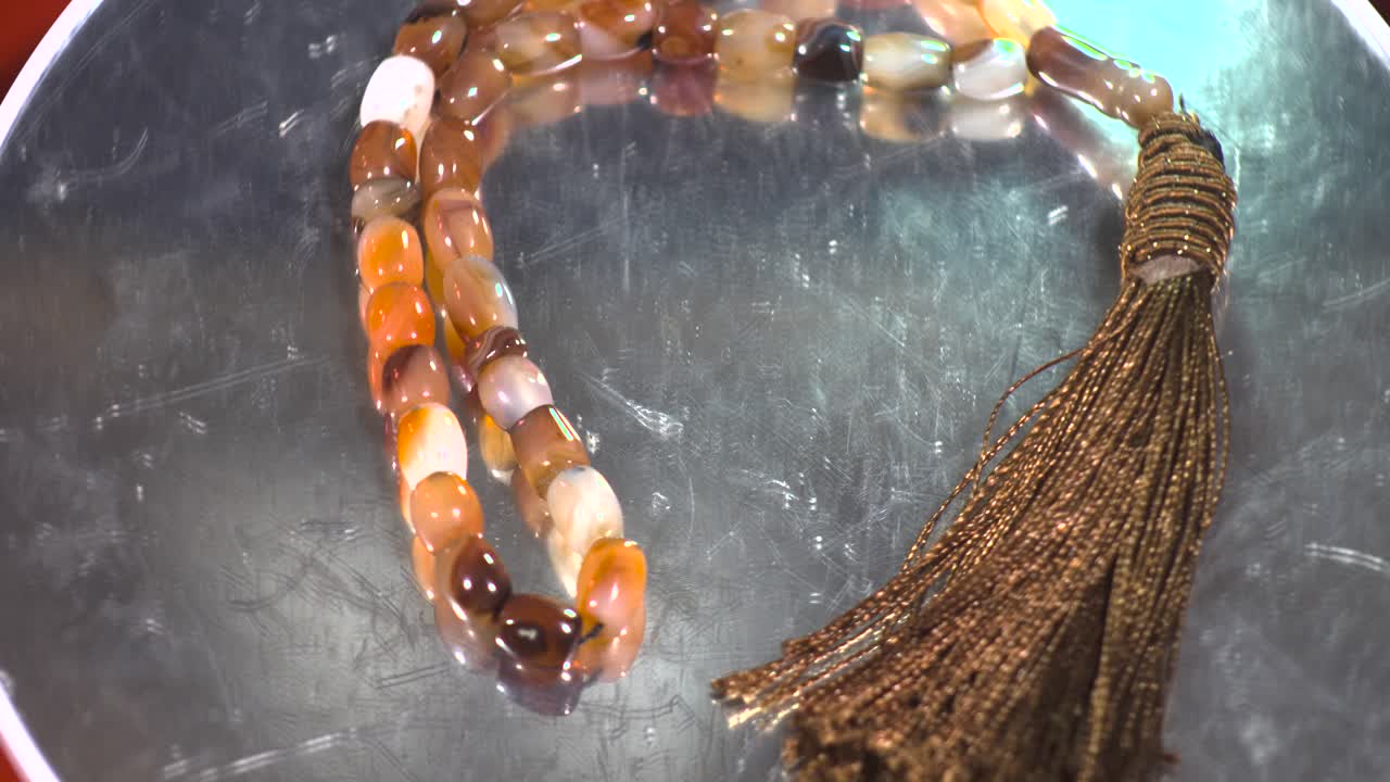 Top-down view for rosary beads pincer red gems on turntable slow motion