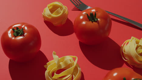 video de tomates rojos frescos y nidos de pasta con tenedor en fondo rojo