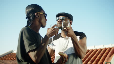 Medium-shot-of-happy-gays-clinking-glasses-of-wine-on-rooftop