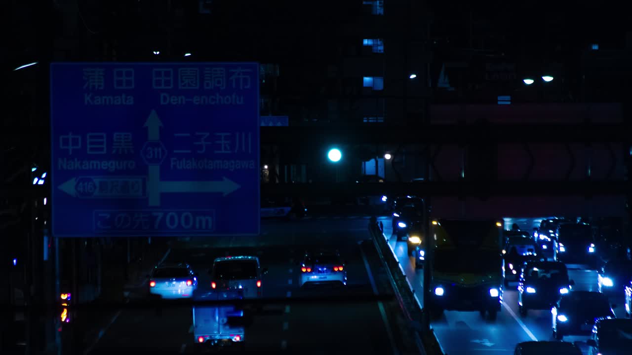 Timelapse notturno del traffico in una strada di Tokyo, in campo lungo.