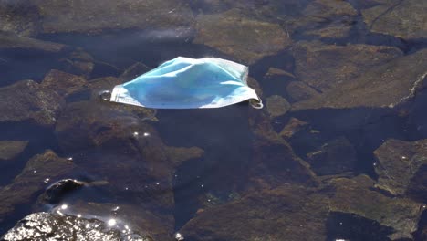 Gebrauchte-Gesichtsmaske-Aus-Der-Covid-19-Pandemie,-Die-Im-Norwegischen-Fjord-Schwimmt