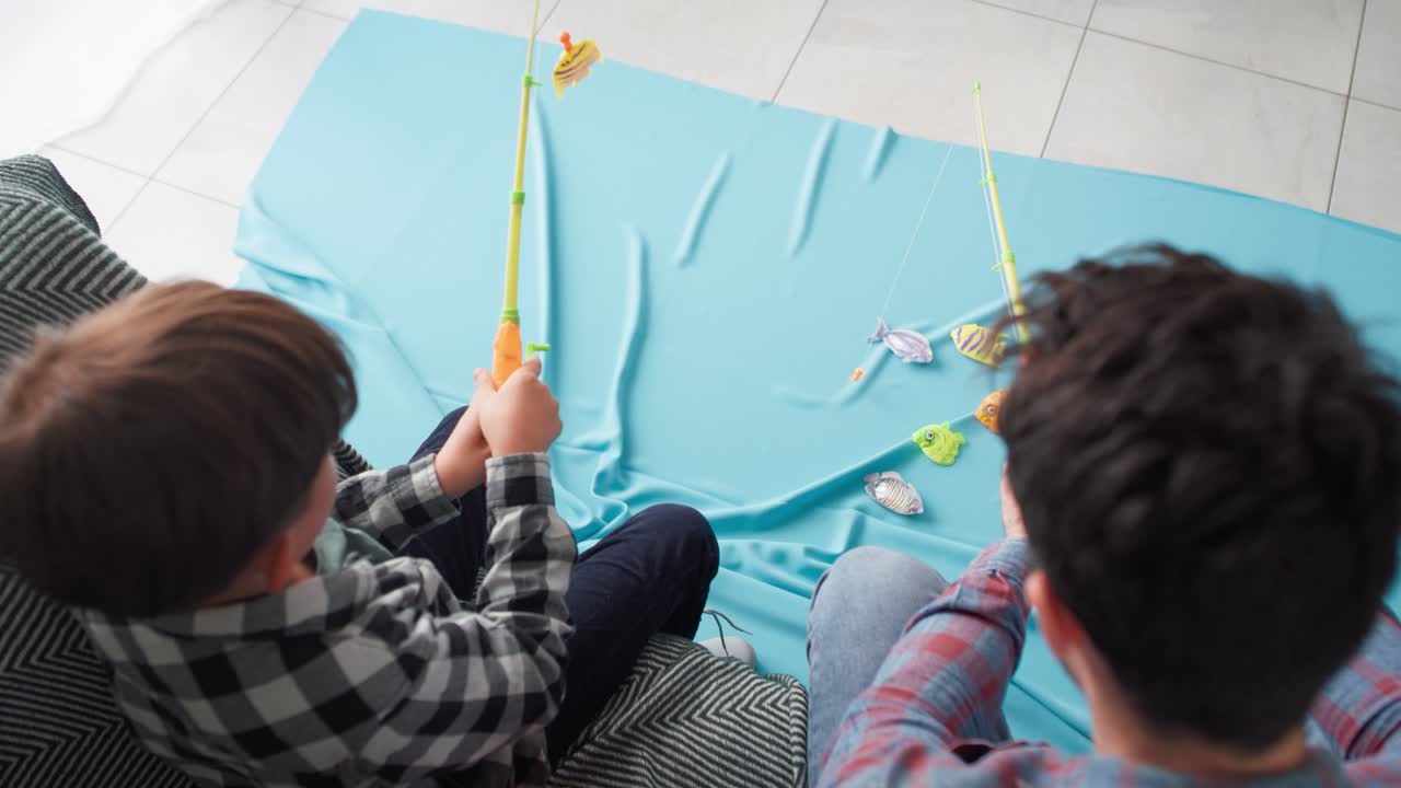vista superior de un niño con su padre jugando a la pesca en casa