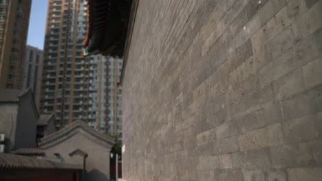 ancient-gray-wall-with-flower-sculpture-with-modern-buildings-in-the-background