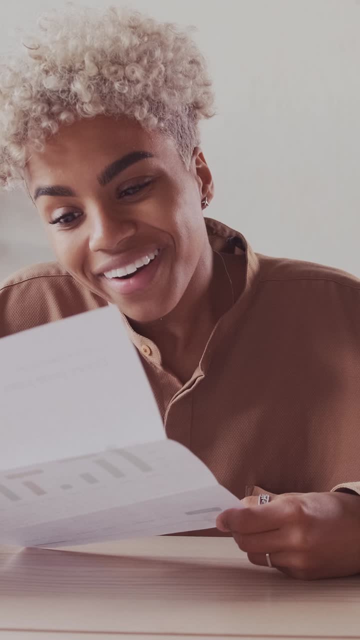 Young happy african american woman investor laughing unfolded paper report