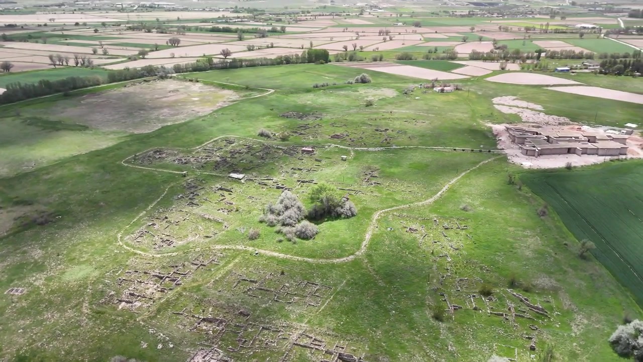 Pemandangan udara drone reruntuhan Kota Kuno Gordion yang dikelilingi oleh lahan pertanian hijau dan lanskap arkeologi di Provinsi Ankara, Turki.