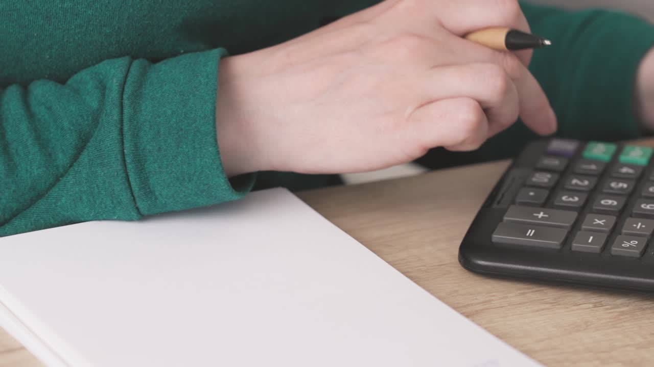 close-up female hands fingers counting on calculator writing numbers summary
